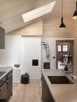 Detailfoto des alten Kamins im Umbau eines Walliserhauses in Lax, Goms: Blick von der offenen Küche auf den historischen Kamin, kombiniert mit modernen Designmerkmalen, entworfen von Architektur Holzer GmbH.