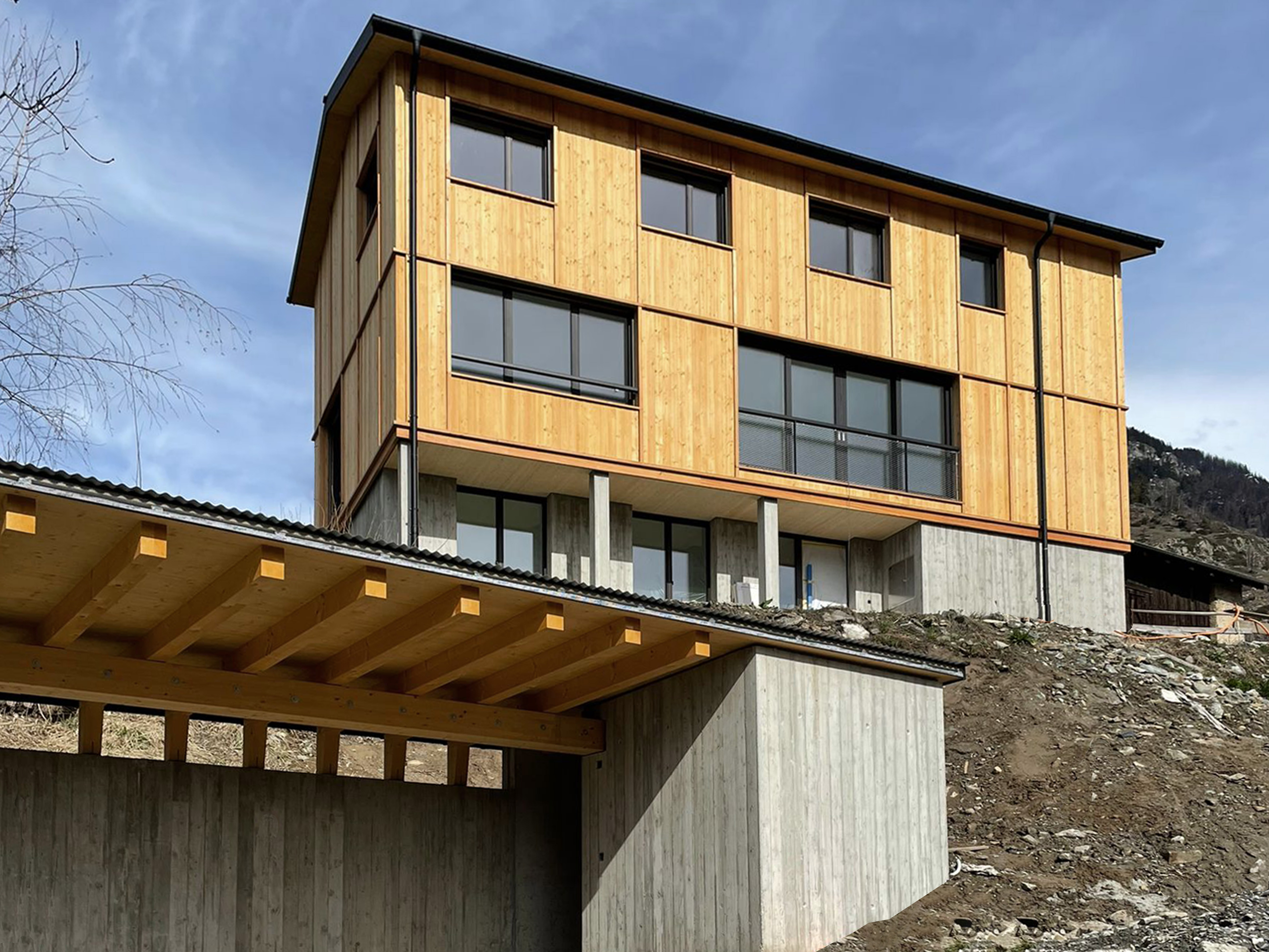 Einfamilienhaus in Naters, Hegdron: Holzhaus mit markanter Holzfassade im Rasterdesign, separat stehendes Carport, entworfen von Architektur Holzer GmbH.