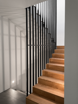 Treppenhaus im Einfamilienhaus in Ried-Brig: Massivtreppe aus Parkett mit geschossübergreifendem Stakettengeländer, modernes Design von Architektur Holzer GmbH.